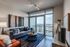 Modern living room with elegant decor, large window providing stunning cityscape views, stylish furniture, and chic artwork.