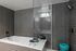 Sleek modern bathroom featuring a luxurious soaking tub, elegant gray tile walls, and stylish fixtures.