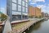 Contemporary waterfront apartment complex with sleek glass facade and scenic boardwalk access, offering modern urban living.