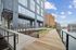 Modern riverside apartment complex with sleek architecture, featuring a wooden walkway and scenic water views under a clear blue sky.