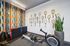 Contemporary fitness room with a rowing machine, vibrant geometric wall design, and decorative vintage tennis racquet display.