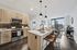 Contemporary kitchen with sleek wooden cabinetry and modern lighting, featuring a stylish breakfast bar with stunning cityscape views.