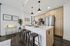 Modern kitchen with sleek island seating, elegant lighting, and contemporary stainless steel appliances.