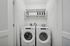 Modern laundry room with sleek white washer and dryer, open shelving, and stylish storage solutions.