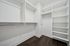 Sleek and spacious walk-in closet with ample shelving and hanging space, featuring elegant dark hardwood flooring.