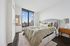 Elegant bedroom with a plush bed, large window showcasing a stunning city view, and stylish decor with neutral tones.