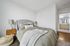 Elegant bedroom with a plush grey headboard, stylish bedside lamps, and textured bedding, showcasing a serene escape leading to a modern en-suite bathroom.