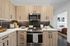 Modern kitchen with sleek cabinetry, stainless steel appliances, and a sophisticated backsplash, opening into a cozy bedroom.