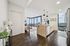 Modern open-concept apartment with sleek kitchen island, elegant decor, and panoramic city view through large windows.