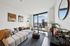 Modern living room with chic decor, plush sofa, and stunning cityscape views through large windows.