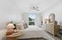 Bright and inviting bedroom with a cozy bed, elegant wooden furniture, and a large window offering serene outdoor views.