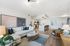 Bright and modern living room with open-concept kitchen, featuring stylish decor, a cozy white sectional sofa, and a sleek wooden coffee table.