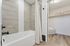 Modern bathroom with elegant wood-style tiles, a sleek white bathtub, and a spacious walk-in closet.