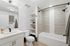 Contemporary bathroom with sleek vanity, spacious bathtub, and elegant shelving in a modern apartment.