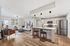 Elegant open-plan living room and kitchen with modern decor, featuring a cozy seating area, stylish kitchen island, and sleek stainless steel appliances.