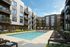 Modern apartment complex with a sparkling pool, surrounded by stylish balconies and lush landscaping, perfect for upscale urban living.