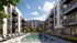 Luxurious apartment complex featuring a pristine outdoor pool, surrounded by stylish sun loungers, vibrant landscaping, and modern balconies under a clear blue sky.