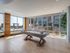 Bright and modern recreational room with a sleek pool table, showcasing floor-to-ceiling windows and outdoor views in a luxury apartment building.