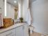 Modern bathroom with elegant white cabinetry, stylish countertop, and cozy lighting, featuring chic wicker storage baskets.