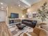 Elegant living room with modern decor, featuring a comfortable sofa, stylish chairs, and tasteful artwork under soft lighting.