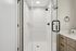 Modern bathroom with glass shower door, elegant white tiles, and sleek fixtures creating a sophisticated ambiance.