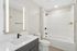 Sleek modern bathroom featuring a stylish mirror, elegant white vanity, and a well-designed tub with vertical tile details.