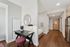 Modern apartment entryway with stylish desk area, round mirror, and sleek wood flooring.