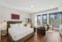 Modern apartment with a cozy bed, stylish decor, and large windows offering stunning city views.