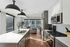 Modern kitchen with sleek appliances and large windows opening into a cozy living room, perfect for urban living.