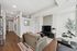 Modern apartment living room featuring sleek furniture, a large TV on a stylish console, and an elegant dining area with natural light.