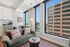 Modern apartment living room with stylish decor, featuring a cozy sofa, chic coffee table, and large windows offering stunning city views.