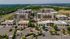 Vibrant aerial view of a modern shopping and residential complex surrounded by lush greenery, showcasing spacious parking and excellent accessibility.