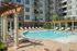 Luxurious apartment complex featuring a pristine swimming pool surrounded by stylish lounge chairs and elegant pergolas.