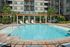 Luxurious apartment complex featuring a sparkling outdoor pool with elegant poolside loungers and lush, landscaped surroundings.
