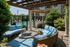 Inviting outdoor patio with cozy wicker seating, stylish blue cushions, and a modern fire pit, offering a relaxing view of the sparkling community pool.
