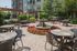 Charming outdoor patio featuring elegant wicker seating, vibrant flower beds, and a central fountain, perfect for relaxation and gatherings.