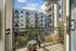 Charming apartment balcony with cozy seating overlooking lush greenery and modern urban architecture.
