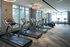 Modern fitness center with multiple treadmills and exercise bikes, featuring floor-to-ceiling windows for natural light.