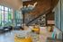 Chic and vibrant lobby with modern furnishings, featuring bold yellow chairs and a stylish geometric wall art under a sleek staircase.