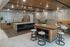 Modern lounge kitchen area with sleek stainless steel appliances, elegant wooden cabinetry, and a stylish island with bar stools, complemented by a cozy seating nook.