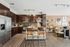 Modern open-concept kitchen and living area featuring sleek dark wood cabinetry, stainless steel appliances, and stylish seating with elegant decor.