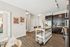 Chic apartment interior showcasing a modern kitchen with sleek dark cabinets, stylish bar stools at a central island, and contemporary decor in an open layout.