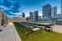 Chic rooftop swimming pool with lounge chairs and ambient string lights overlooking stunning cityscape at dusk.