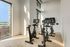 Bright and modern fitness room with high-tech stationary bikes and large windows showcasing city views.