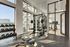 Bright and modern gym featuring state-of-the-art equipment, including weight racks, exercise machines, and panoramic city views.