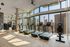 Modern gym with multiple treadmills and cityscape views through expansive floor-to-ceiling windows.