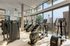 Modern gym with state-of-the-art equipment, large windows offering stunning city views, and abundant natural light.