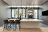Elegant modern kitchen with a sleek island, stylish bar stools, and large windows offering abundant natural light.