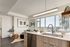 Modern kitchen with sleek countertops, integrated appliances, and a breathtaking city view from large windows.