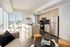 Modern urban apartment with elegant open-plan kitchen, cozy seating area, and expansive city views through large windows.